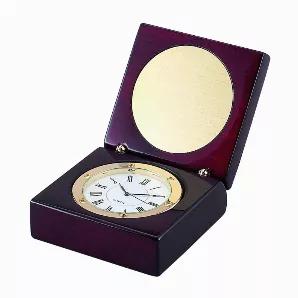 Looking for the perfect corporate gift? Stop wasting your time! Our square hinged wood box with a rosewood finish opens to reveal a round clock face with gold trim and Quartz movement. Inside the lid, there is also a round brass 2.25" diameter engraving plate that is included. The engraving plate sits in a pre cut recess. Once you add your engraving, the adhesive back is peeled off the engraving plate and it just sticks into place. Overall dimensions of the box are 2.875" x 2.875" x 1.5". Includ
