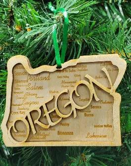 2D Ornament - Representing the great state of Oregon.  Richly detailed with many of Oregon's popular cities and towns engraved on the back layer.  A second layer is applied to the top with the outline word OREGON cut via a precision laser process.  3.5" wide