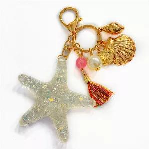 The shimmer of this sea star tassel will make any bag sparkle! Has 6 smaller charms in gold tone.
