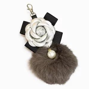 This very posh bag charm comes in 4 classic colors. A vegan leather flower with a black bow, large furry pom-pom with a hanging pearl with rhinestones. You will turn heads when you add this tassel to any of our bags. First-class all the way. Colors: black & white, gold, pink and silver.