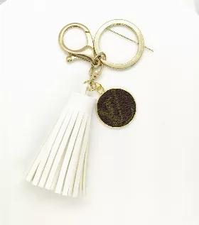 White vegan leather tassel keychain with Louis Vuitton Charm. Charm repurposed from LV Speedy 35 FH1912.