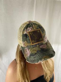 <p>Femininity and Grit Camo and roses trucker cap has one ponytail opening in back. Upcycled with authentic Louis Vuitton materials. Adjustable velcro closure. 70% cotton and 30% polyester. </p><br> <p>Disclaimer: We are not affiliated with Louis Vuitton or it's subsidiaries. The designs are developed by Embellish and we use the materials of the designer.</p>