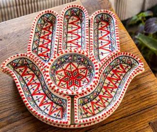 Length: 12.00
Width: 12.00
Height: 2.00
This handmade hamsa dish set is made up of one large plate and six smaller serving or dipping plates. When placed together, the plates create a bright, colorful hamsa hand that symbolizes peace, prosperity, and protection. Each piece is made by local women for a fair wage in Nabeul, Tunisia, a city that's been making renowned ceramics for centuries. The Hamsa Hand Dipping and Serving Platter make for a unique and memorable wedding gift, birthday gift, h