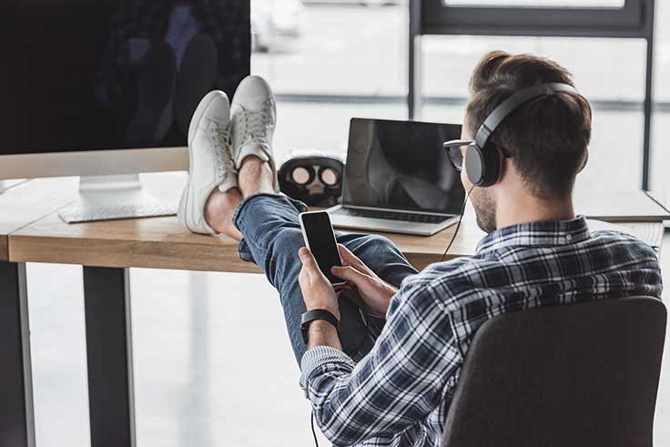 Manwearing headphones and looking at his phone