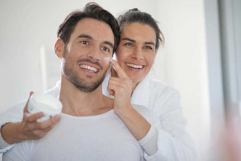 Woman applying face lotion on man's face